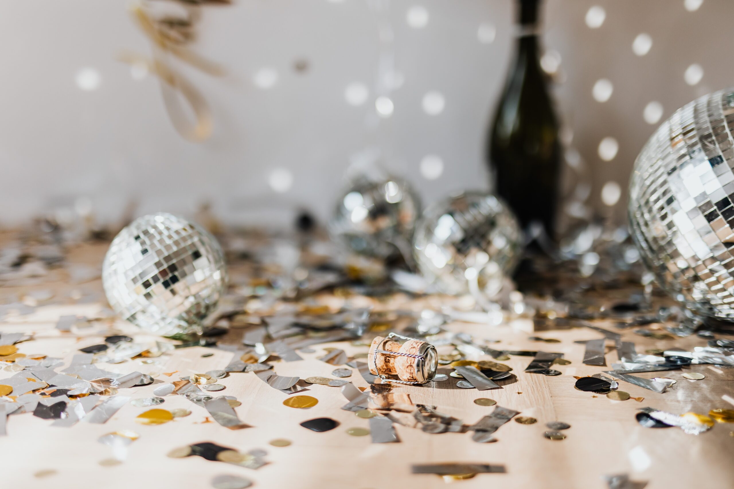 Messy floor after a party with streamers, empty bottle, and other festive items.