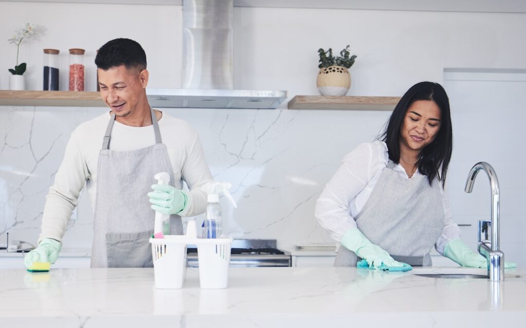 Cleaning company workers clean the kitchen counter together.